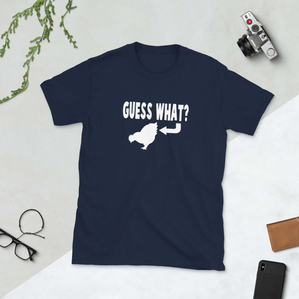 Navy blue t-shirt with an image of a chicken and the words Guess what question mark. There is an arrow pointing to the chickens butt. The graphics are printed on the front of the shirt.