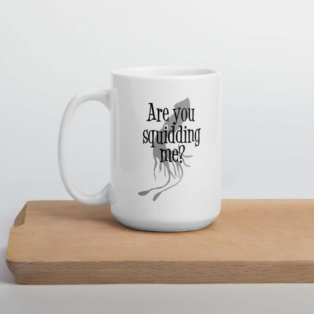 White ceramic coffee mug with an image of a squid and the pun phrase Are you squidding me question mark printed on both sides of the mug.