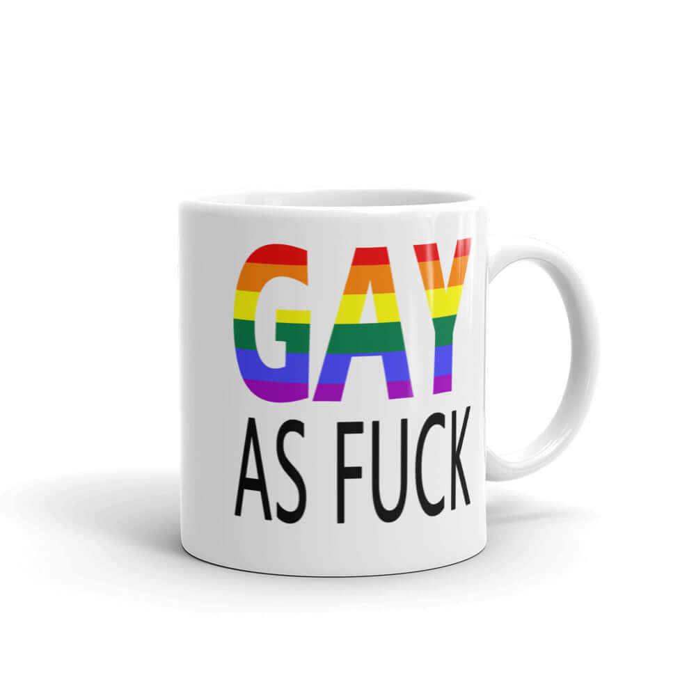 White ceramic mug with the words Gay as fuck printed on both sides. The word Gay is in rainbow stripe font.