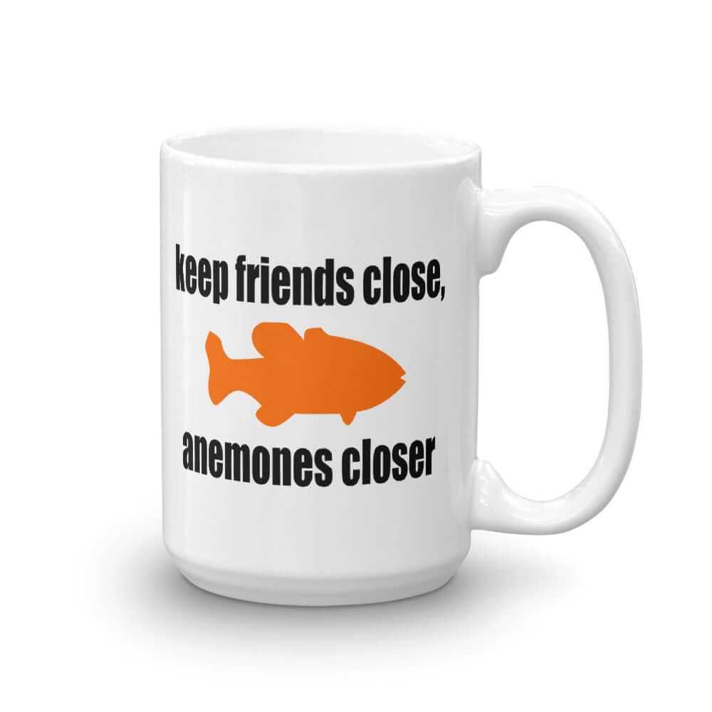 White ceramic coffee mug with the pun phrase Keep friends close, anemones closer with an image of an orange fish printed on both sides of the mug.