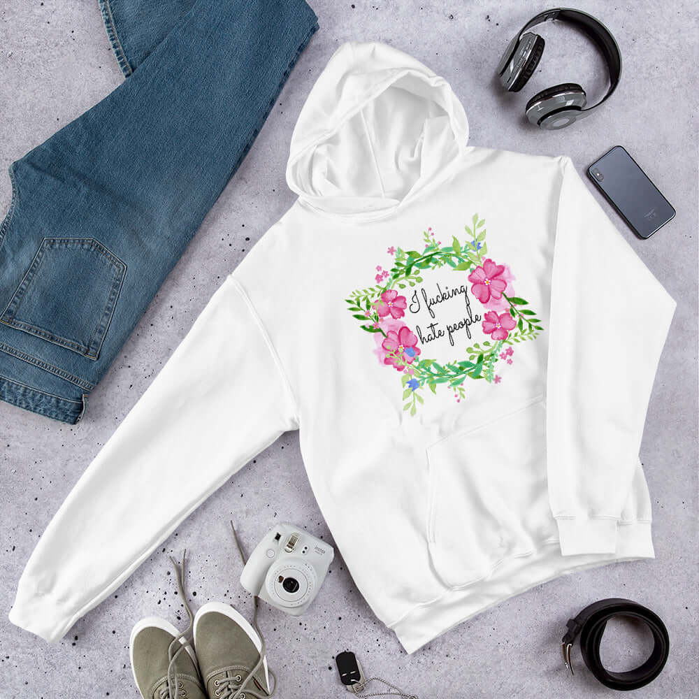 White hooded sweatshirt with pink and green floral wreath image and the words I fucking hate people printed on the front.
