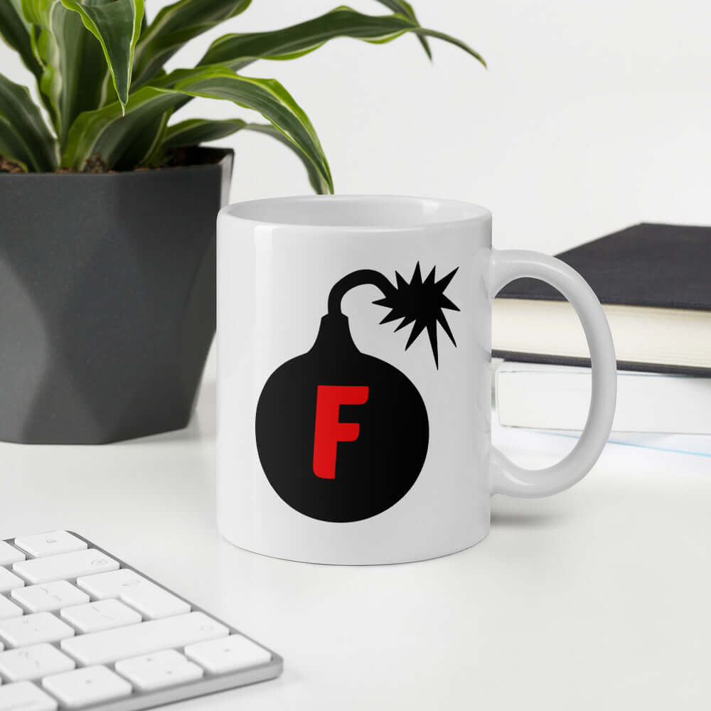 White ceramic coffee mug with an image of a bomb & the letter F printed in the center. The graphics are printed on both sides of the mug.