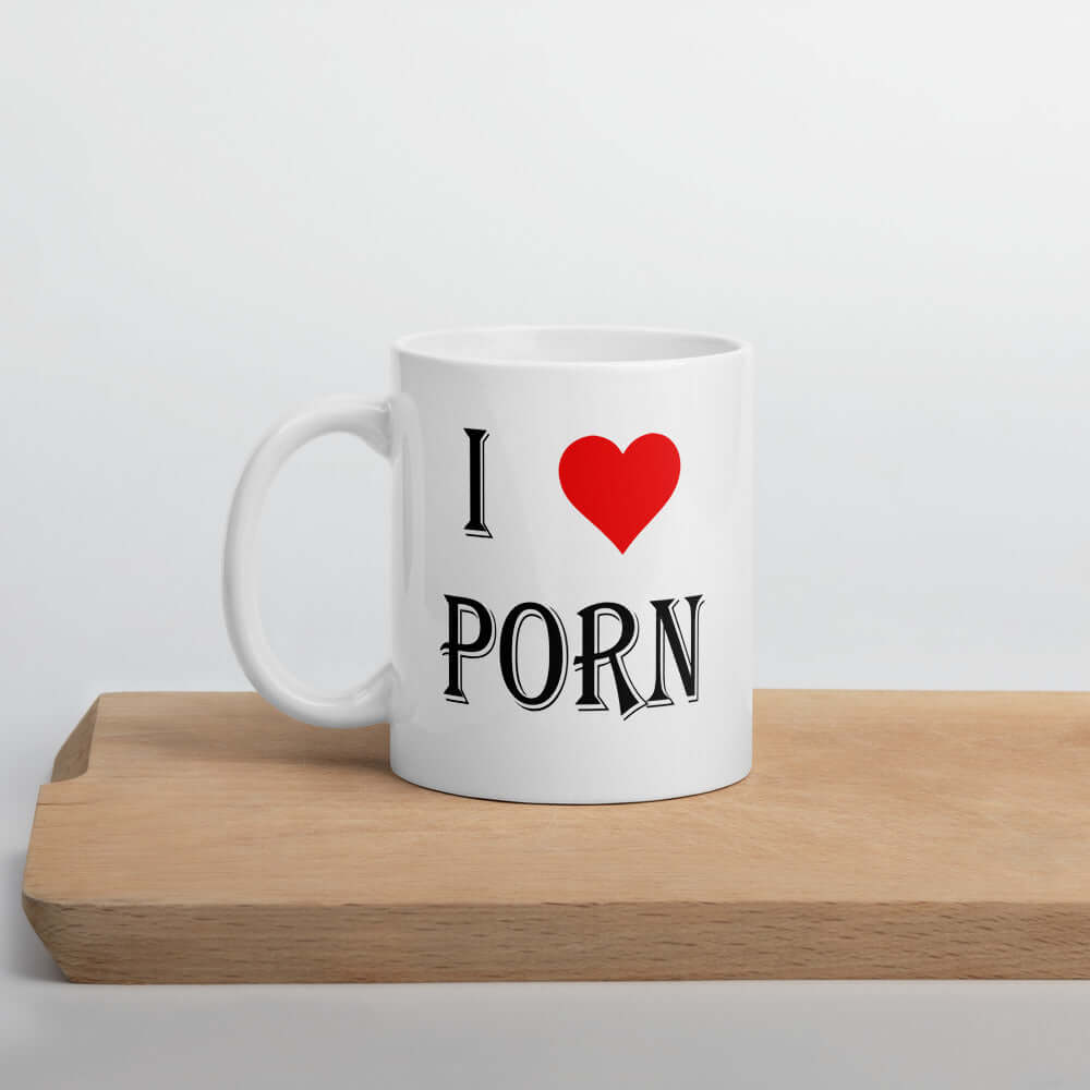 White ceramic coffee mug with the phrase I heart porn printed on both sides of the mug. The heart is red.