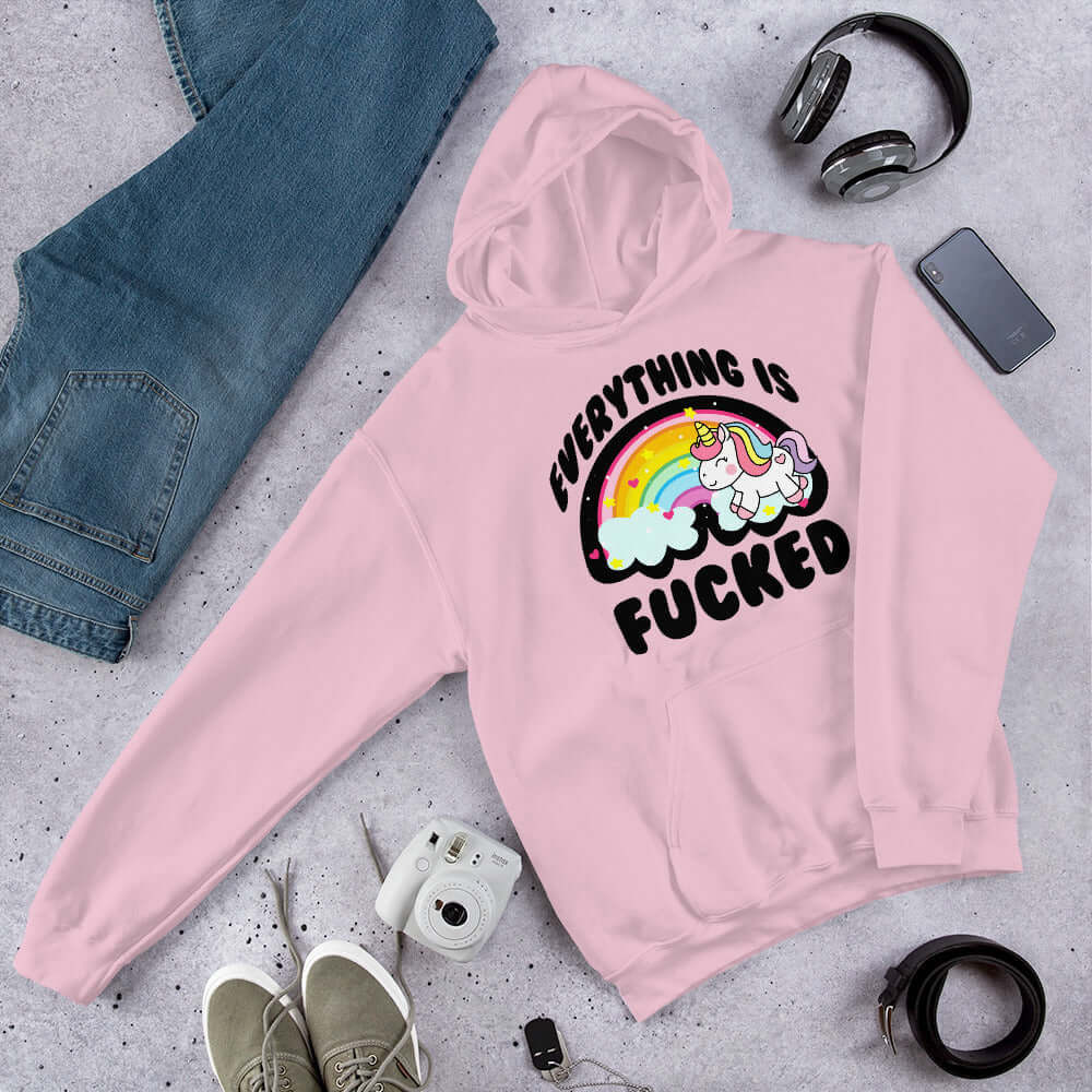 Light pink hoodie sweatshirt with a graphic of a kawaii style unicorn and a pastel rainbow with the words Everything is fucked printed on the front.