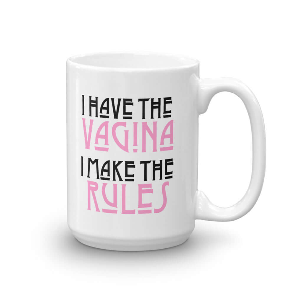 White ceramic coffee mug with the words I have the vagina , I make the rules printed on both sides. The words vagina and rules are pink, the rest of the words are black..