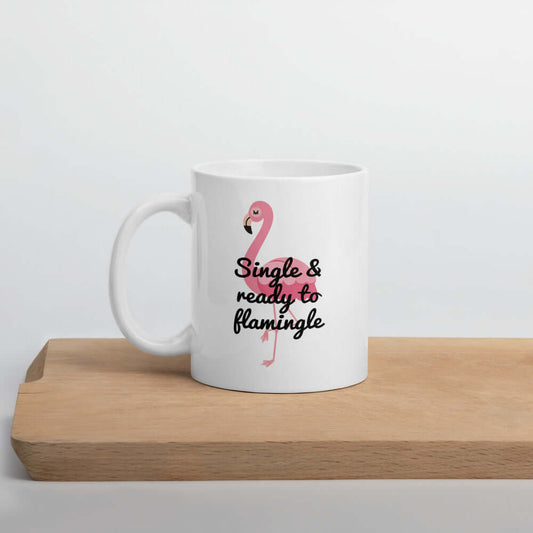 White ceramic coffee mug with image of a flamingo and the words Single and ready to flamingle printed on both sides.