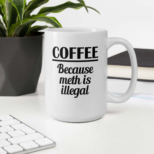 White ceramic coffee mug with the funny phrase Coffee because meth is illegal printed on both sides of the mug.