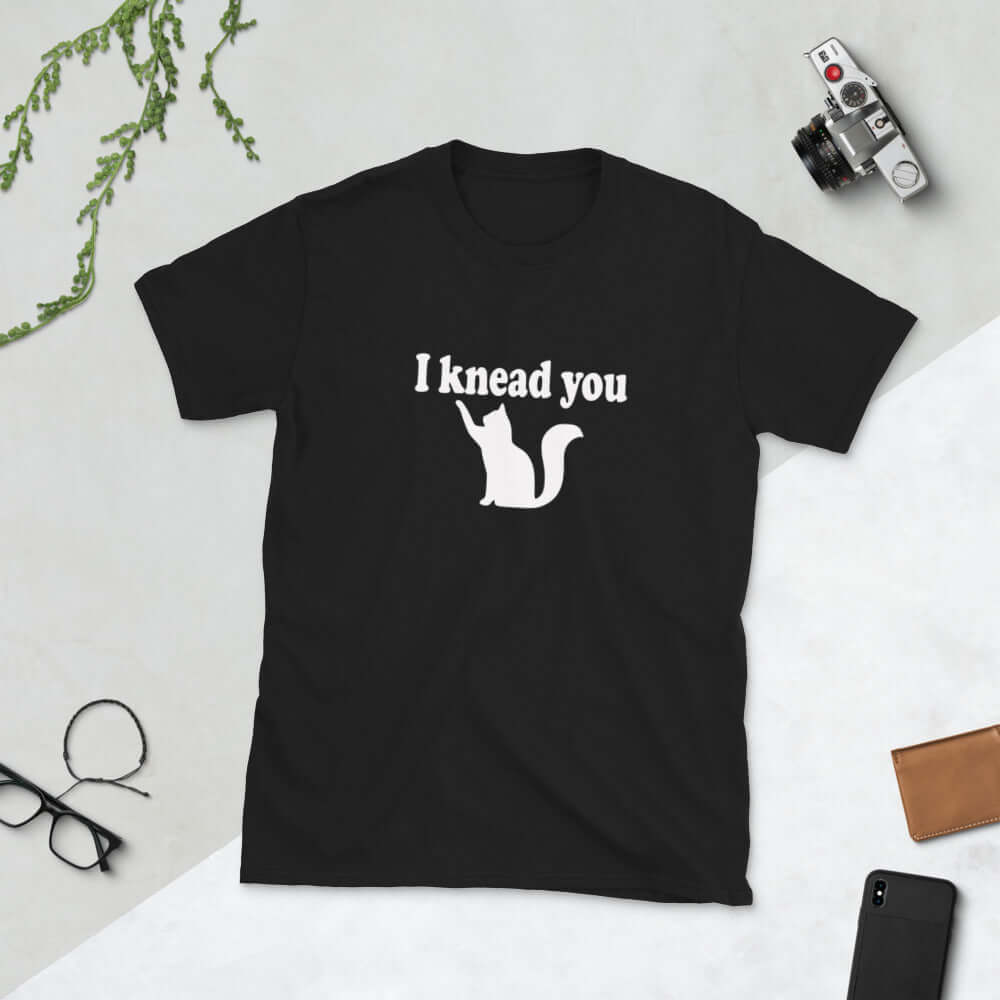 Black t-shirt that has a pun image of a silhouette of a cat and the words I knead you printed on the front.