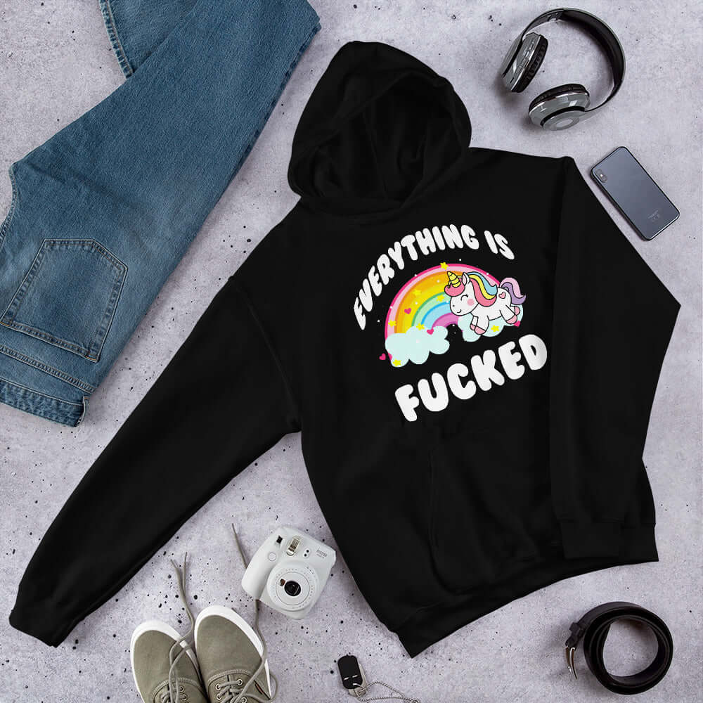 Black hoodie sweatshirt with a graphic of a kawaii style unicorn and a pastel rainbow with the words Everything is fucked printed on the front.