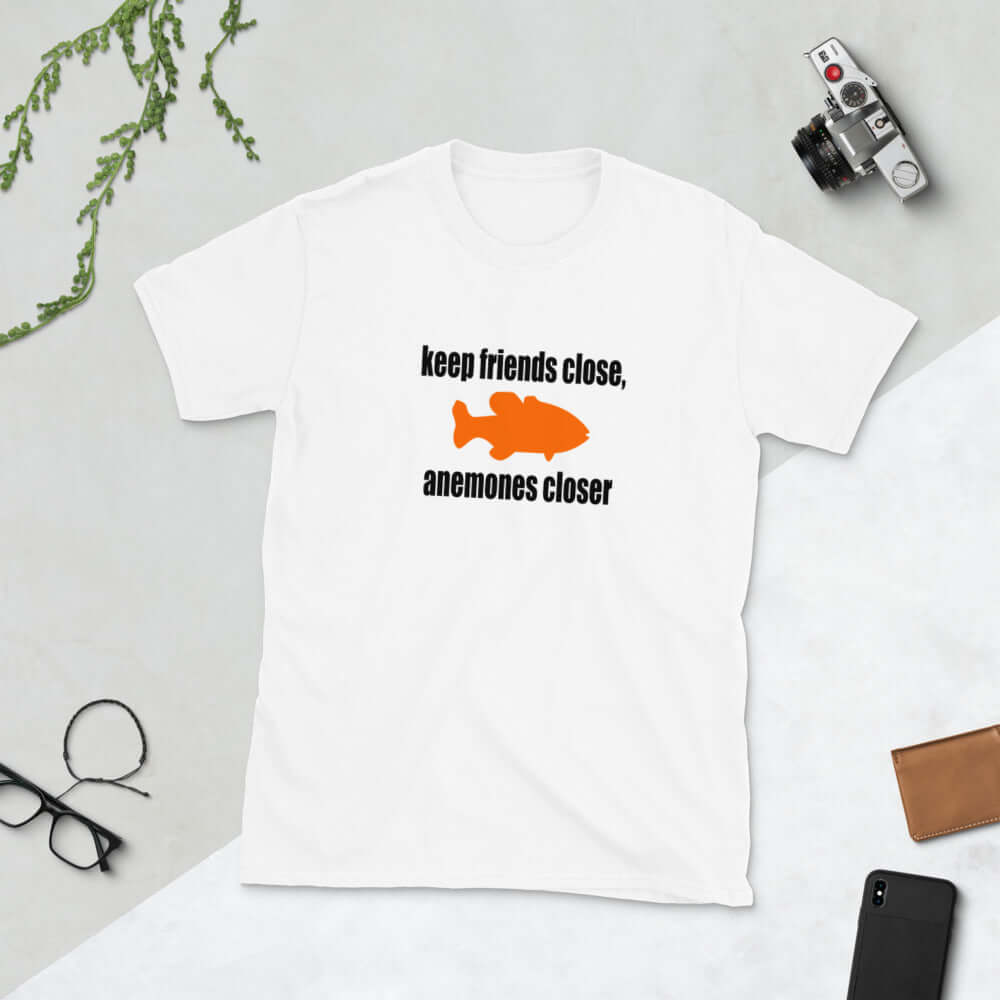 White t-shirt with the pun phrase Keep friends close, anemones closer with an image of an orange fish.