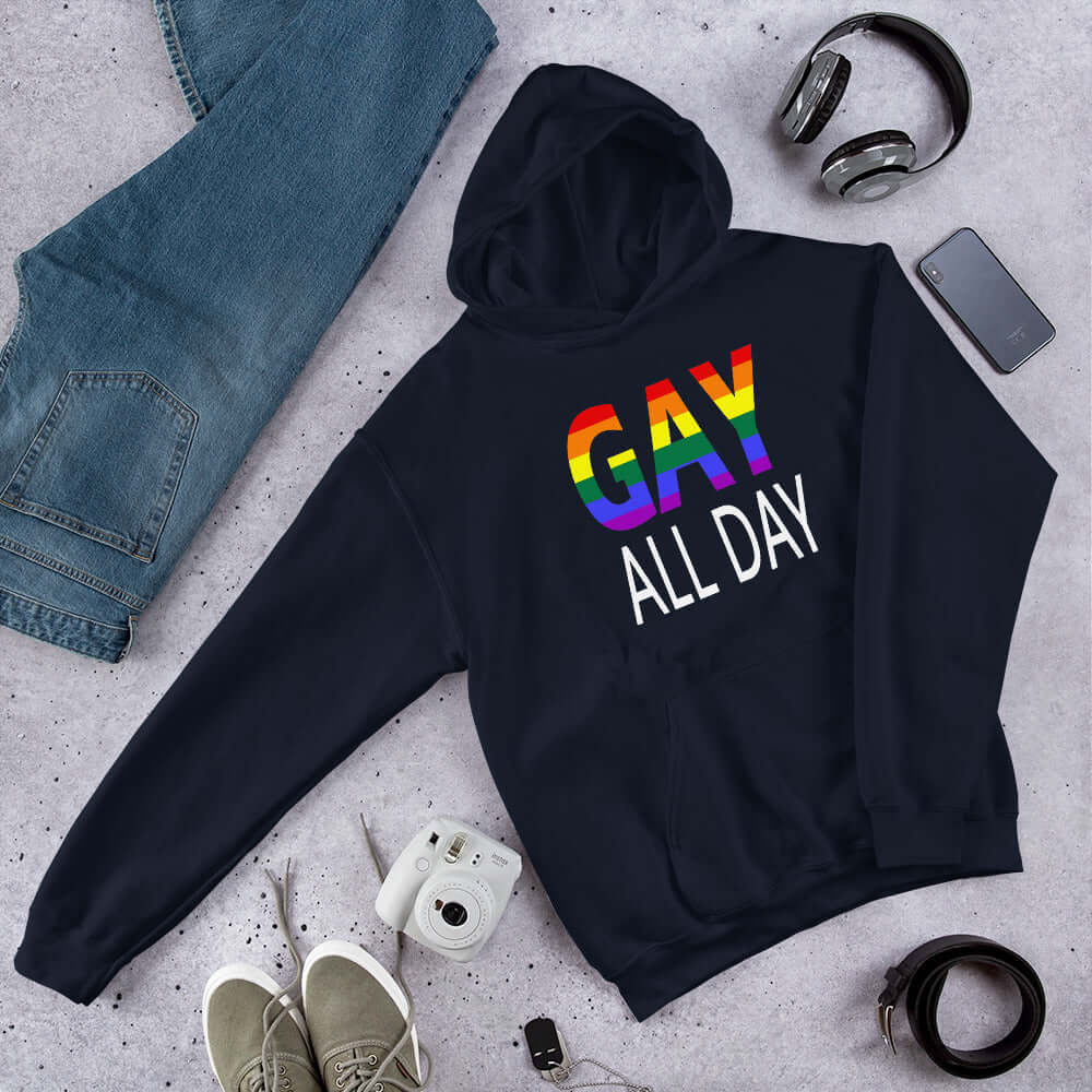 Navy blue hoodie sweatshirt with the words Gay all day printed on the front. The word Gay is in rainbow stripe font. 