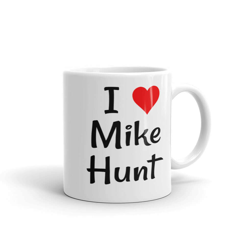 White ceramic coffee mug with pun I heart Mike Hunt printed on both sides of the mug. The heart is red.