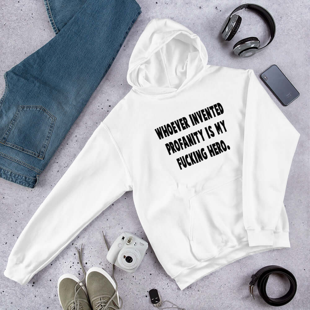 White hoodie sweatshirt with the phrase Whoever invented profanity is my fucking hero printed on the front.