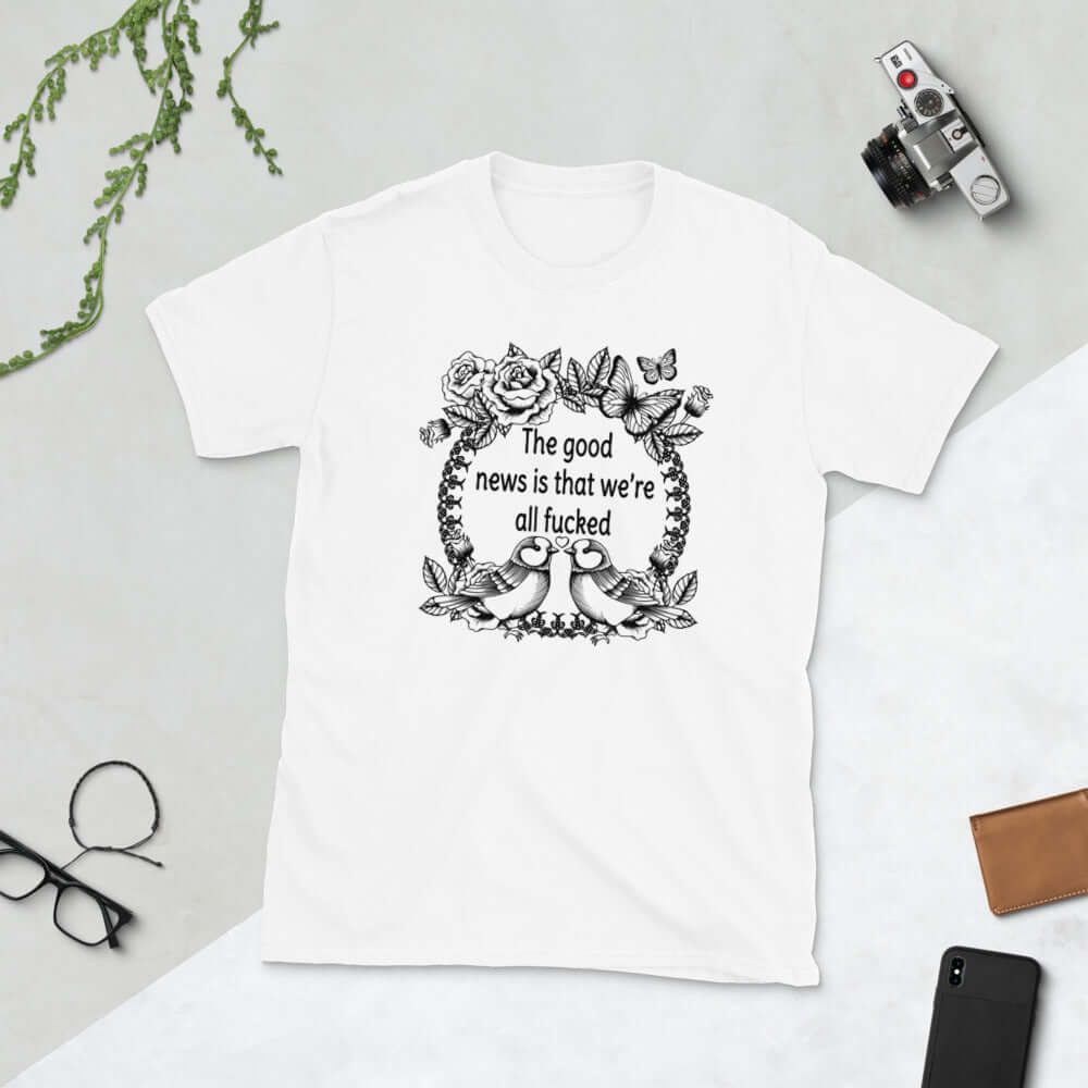 White t-shirt that has an image of a line drawing wreath with butterflies, sparrows and roses. The phrase The good news is that we're all fucked printed inside of the wreath. The graphics are printed on the front of the shirt.