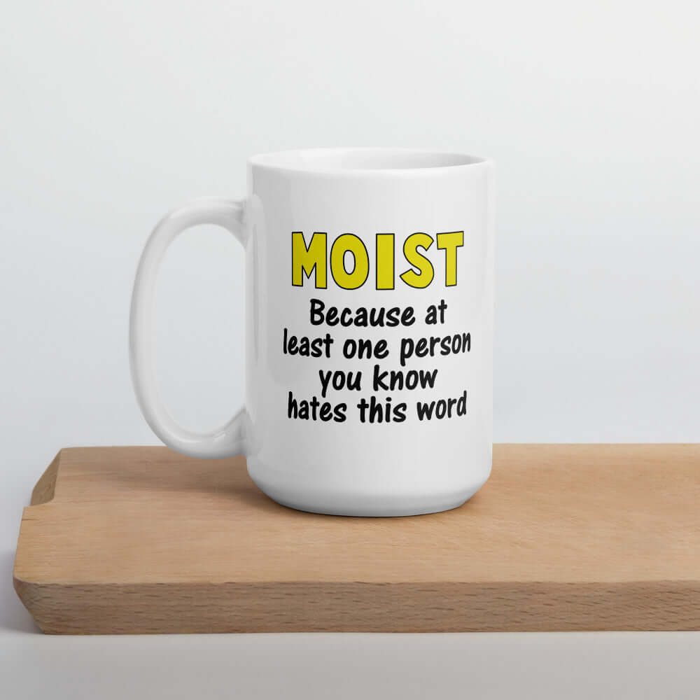 White ceramic coffee mug with the word Moist printed in large yellow bold font. In smaller font under the word moist is the phrase Because at least one person you know hates this word. The text is printed on both sides of the mug.