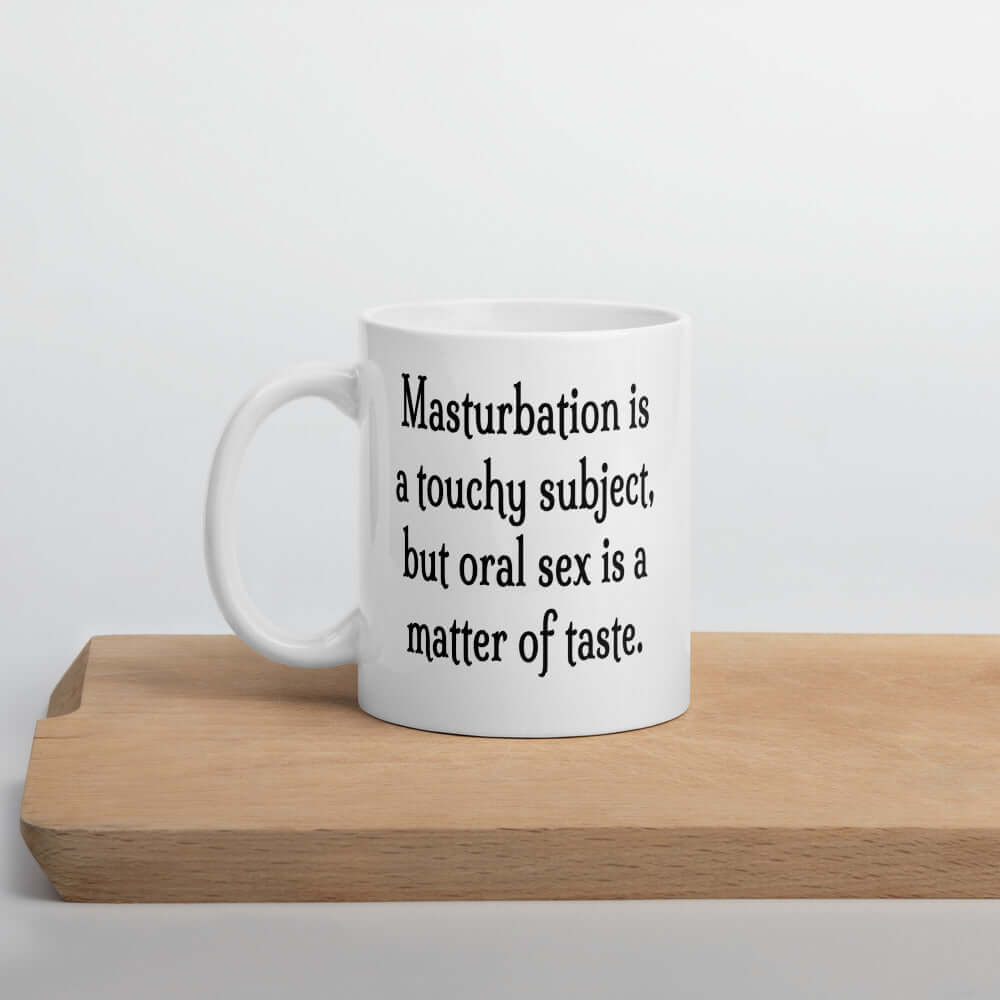 White ceramic coffee mug with the suggestive phrase Masturbation is a touchy subject, but oral sex is a matter of taste printed on both sides of the mug.