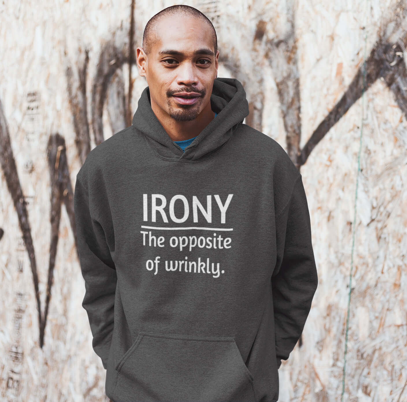 Man wearing a dark grey hoodie sweatshirt with the funny phrase Irony, the opposite of wrinkly printed on the front.