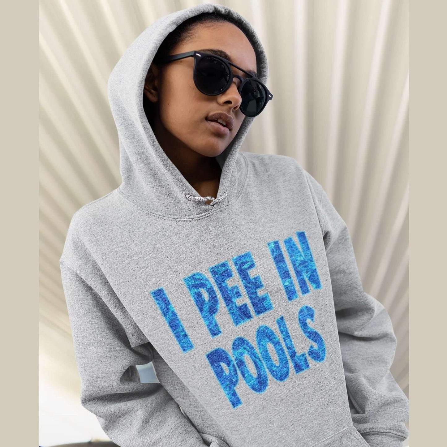 woman wearing sunglasses and hoodie by pool