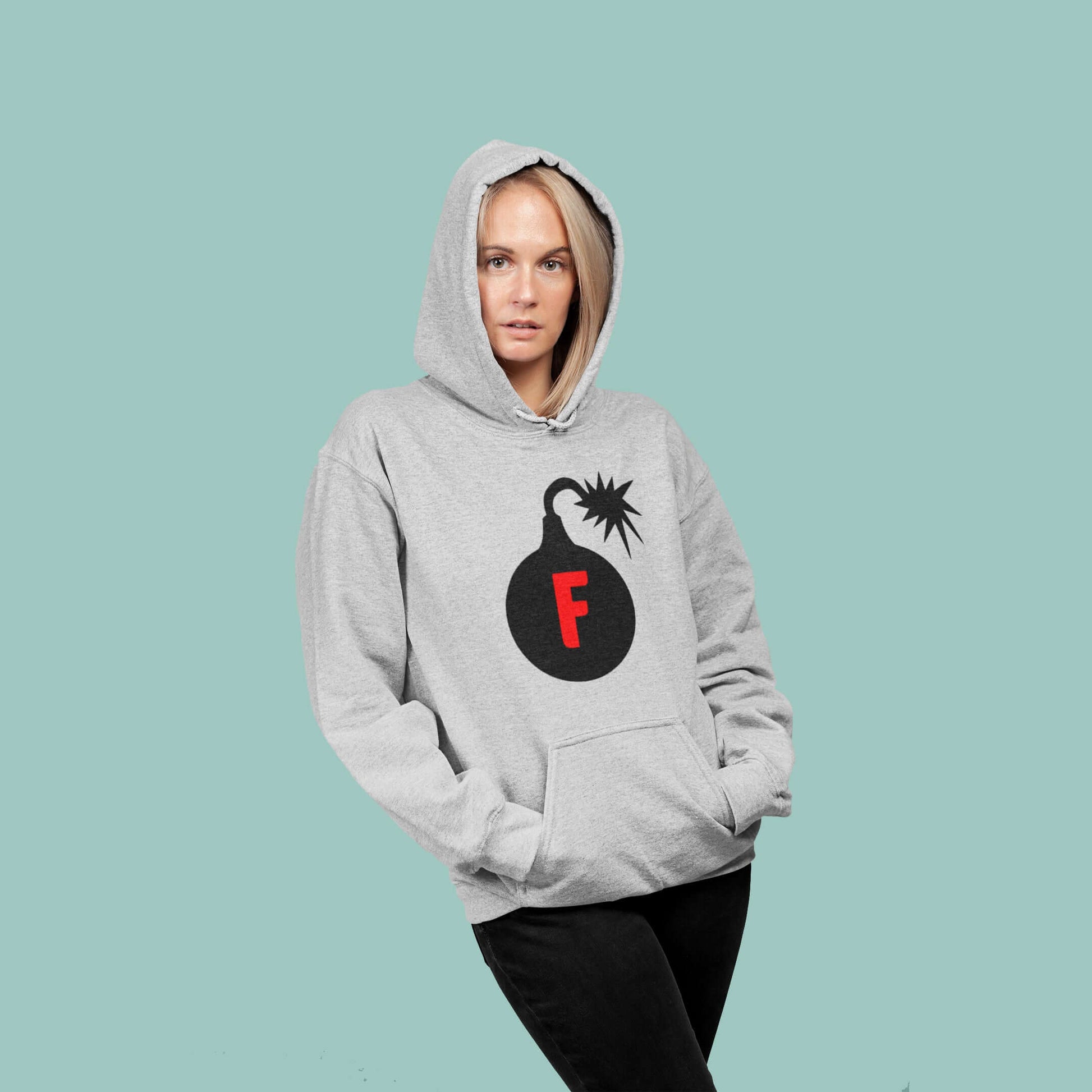 Woman wearing a light grey hoodie sweatshirt with an image of a bomb & the letter F printed in the center. The graphics are printed on the front of the hoodie.