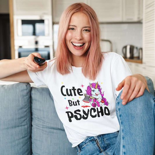 Woman wearing a white t-shirt that has a graphic of a unicorn holding a knife & the words Cute but psycho printed on the front.