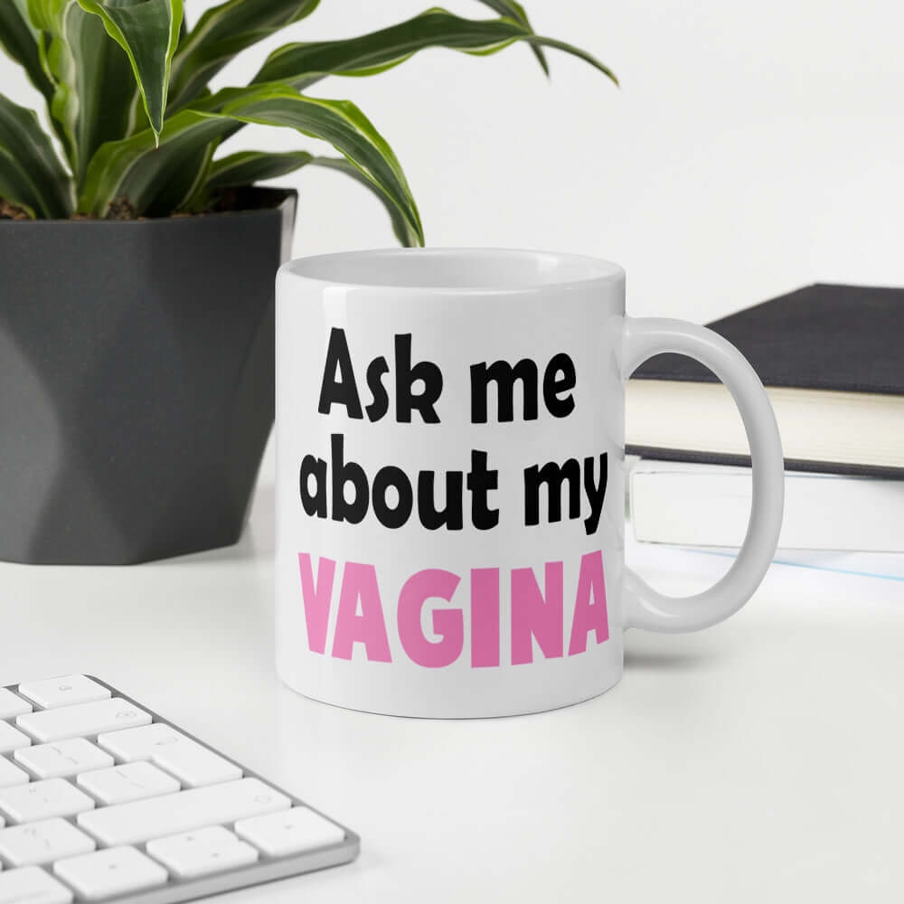 White ceramic mug with the words Ask me about my vagina printed on both sides. The word vagina is printed in pink. The rest of the text is black.