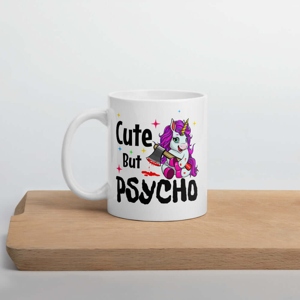 White ceramic coffee mug that has a graphic of a unicorn holding a knife & the words Cute but psycho printed on both sides.