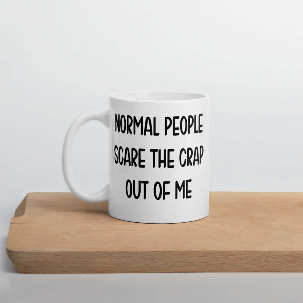 White ceramic coffee mug with the phrase Normal people scare the crap out of me printed on both sides.