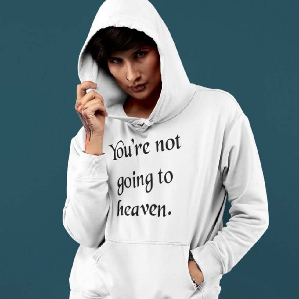 Woman wearing a white hoodie sweatshirt with the phrase You're not going to heaven printed on the front.