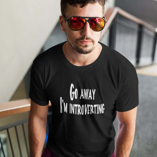 Man wearing sunglasses and a black t-shirt with the phrase Go away, I'm introverting printed on the front of the shirt.