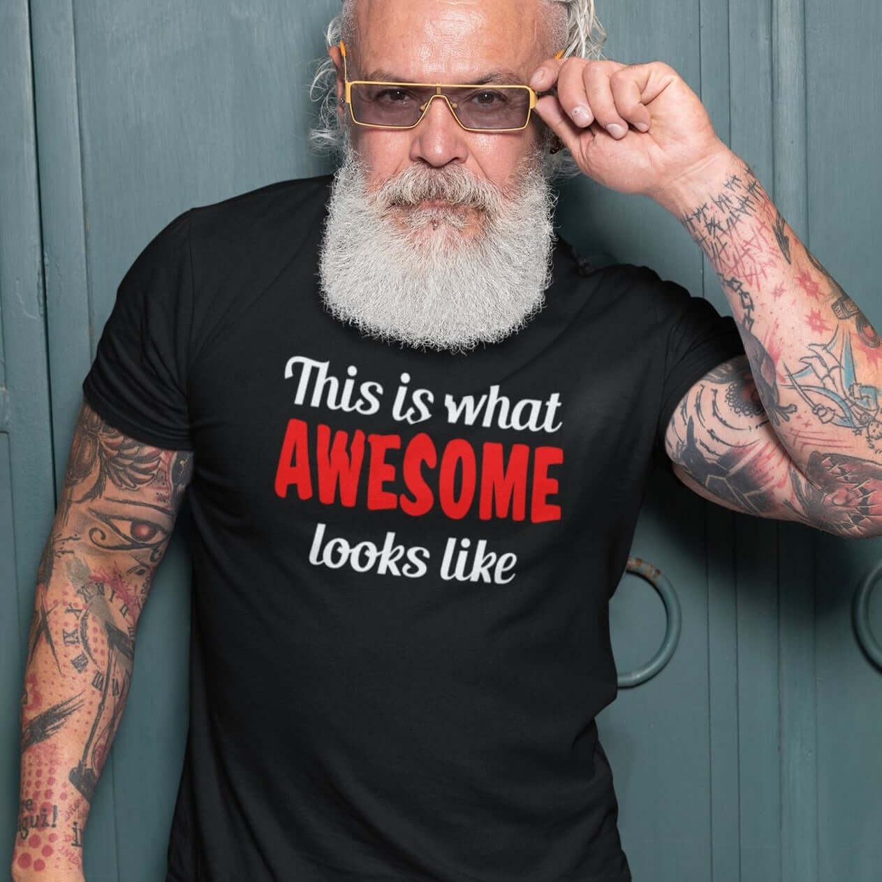 Tattooed bearded man wearing black t-shirt with the words This is what awesome looks like printed on the front. The word awesome is bright red. The rest of the text is white.