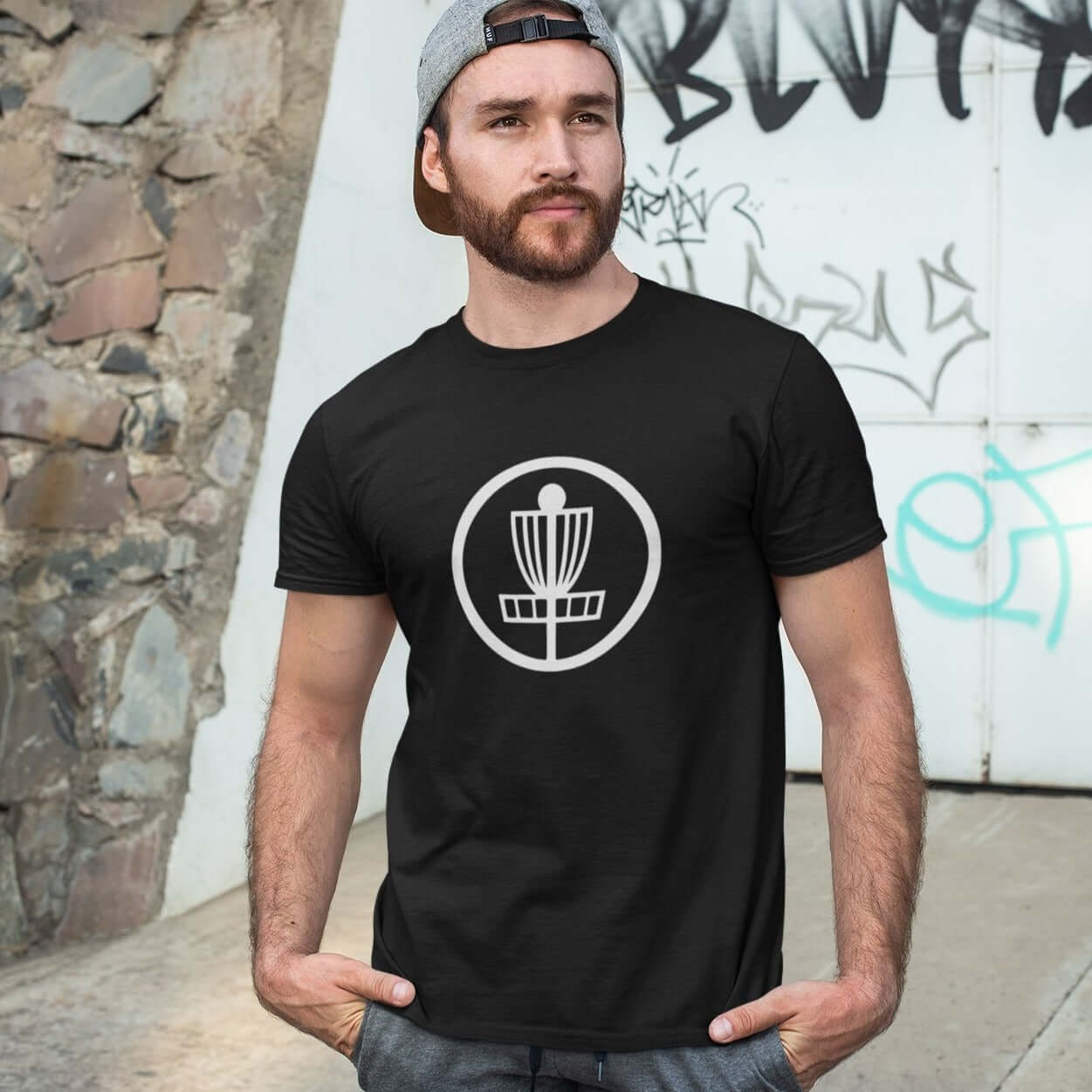 Man wearing a black t-shirt with an image of disc golf basket silhouette with a circle around it printed on the front.