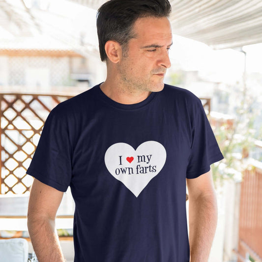 Man wearing a navy blue t-shirt with I heart my own farts printed on the front. The words are printed inside of a larger heart image.