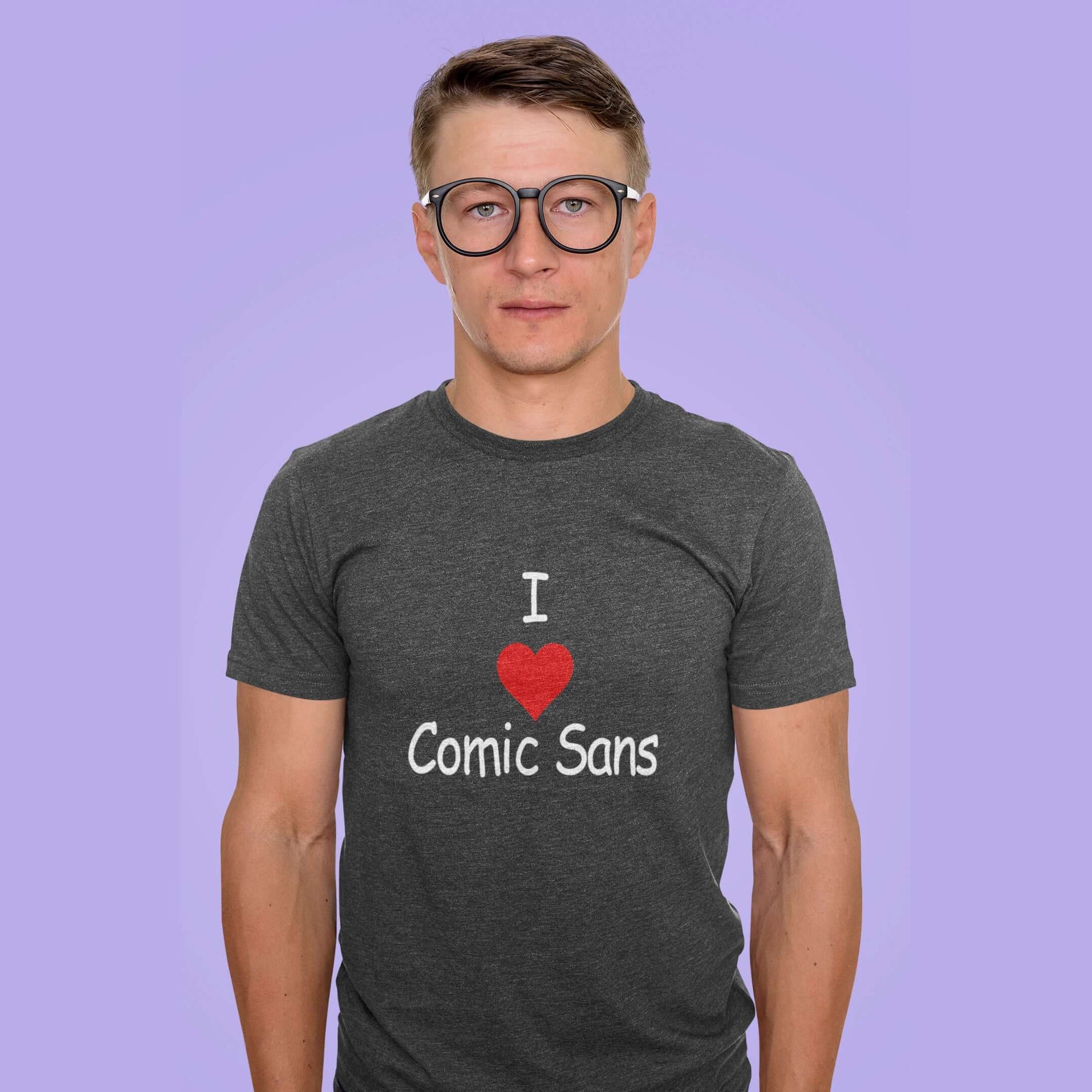 Man wearing a dark heather grey t-shirt with the phrase I heart Comic Sans on the front. The text is in comic sans font.