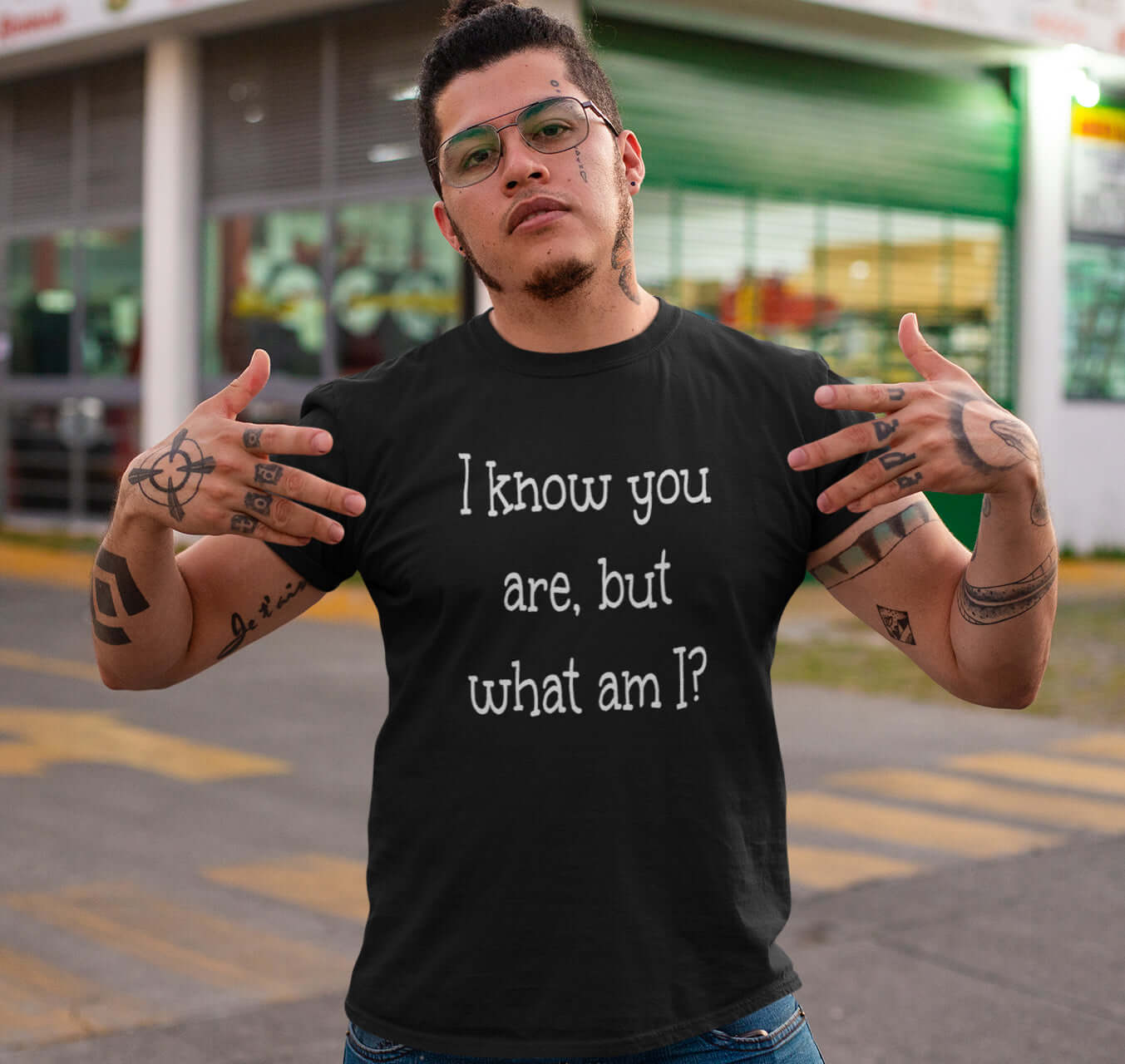 Macho looking man wearing a black t-shirt with the childish phrase I know you are but what am I with a question mark printed on the front.