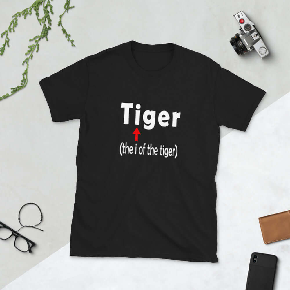 Black t-shirt with the word Tiger and in smaller letters it says the I of the tiger with an arrow pointing to the letting I in the words tiger. The graphics are printed on the front of the shirt.
