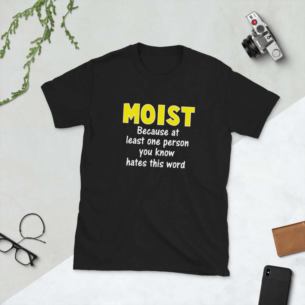 Black t-shirt with the word Moist printed in large yellow bold font. In smaller font under the word moist is the phrase Because at least one person you know hates this word. 