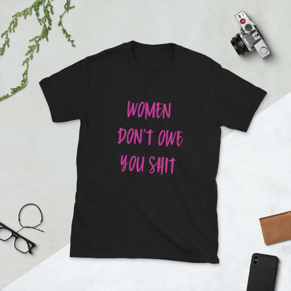 Black t-shirt with the words Women don't owe you shit printed on the front in pink.