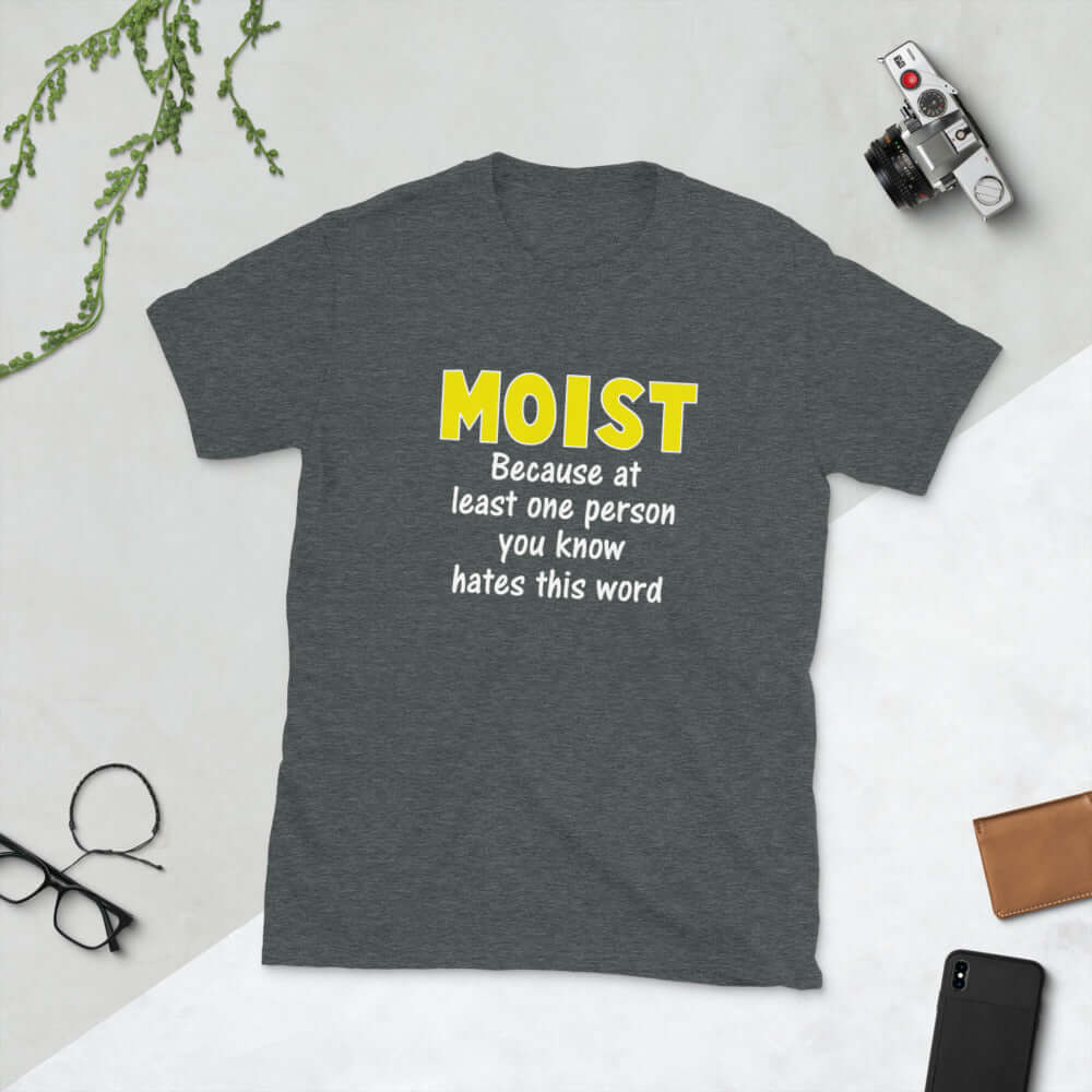 Dark grey t-shirt with the word Moist printed in large yellow bold font. In smaller font under the word moist is the phrase Because at least one person you know hates this word. 