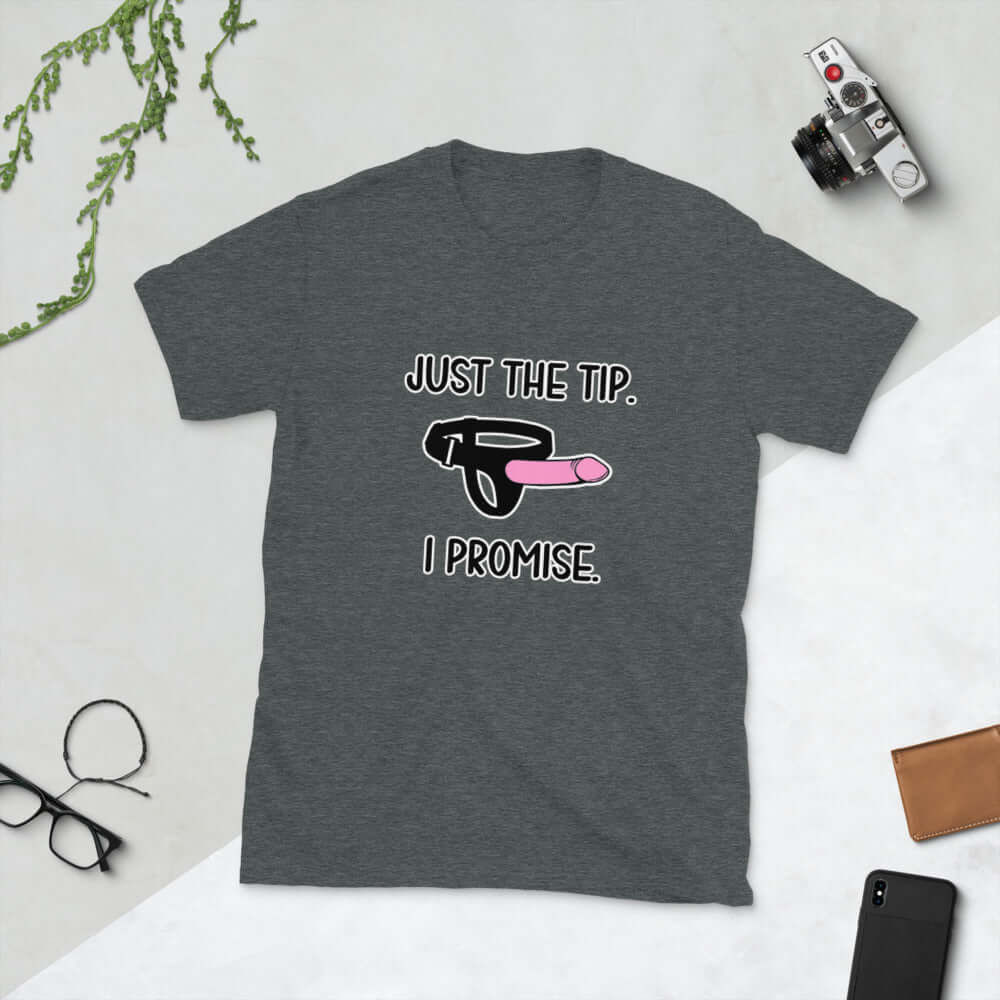 Dark grey t-shirt that has an image of a strap-on dildo and the words Just the tip, I promise printed on the front. The graphics are pink, black and white.