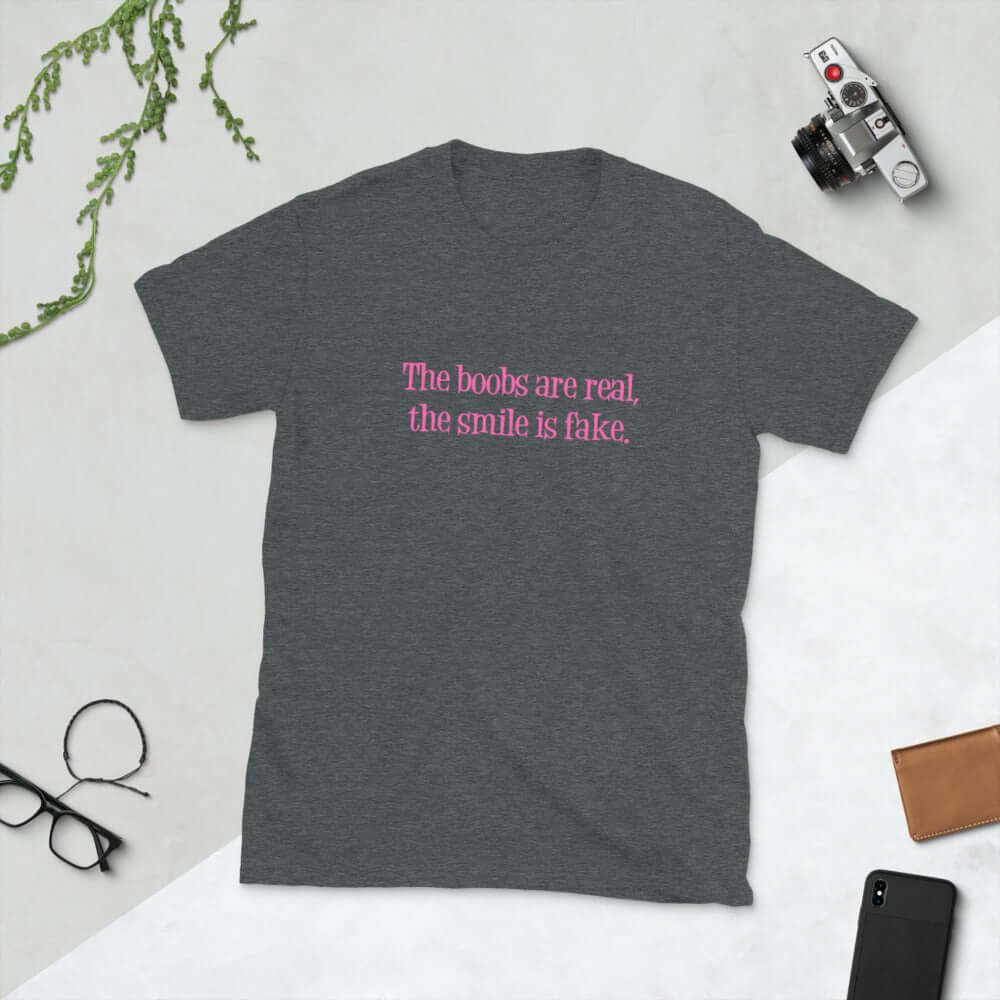 Dark heather grey t-shirt with the phrase The boobs are real, the smile is fake printed in pink on the front.