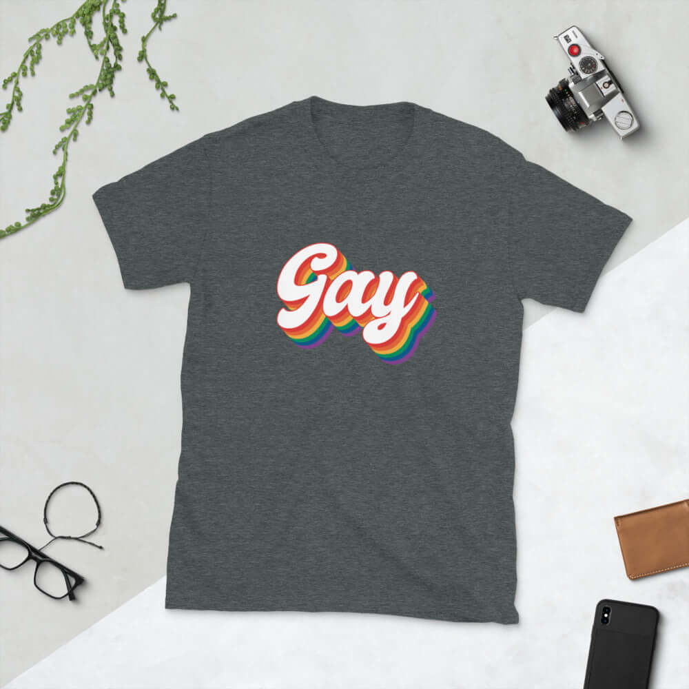 Dark heather grey t-shirt with the word Gay printed on the front. The word gay is outlined in rainbow.