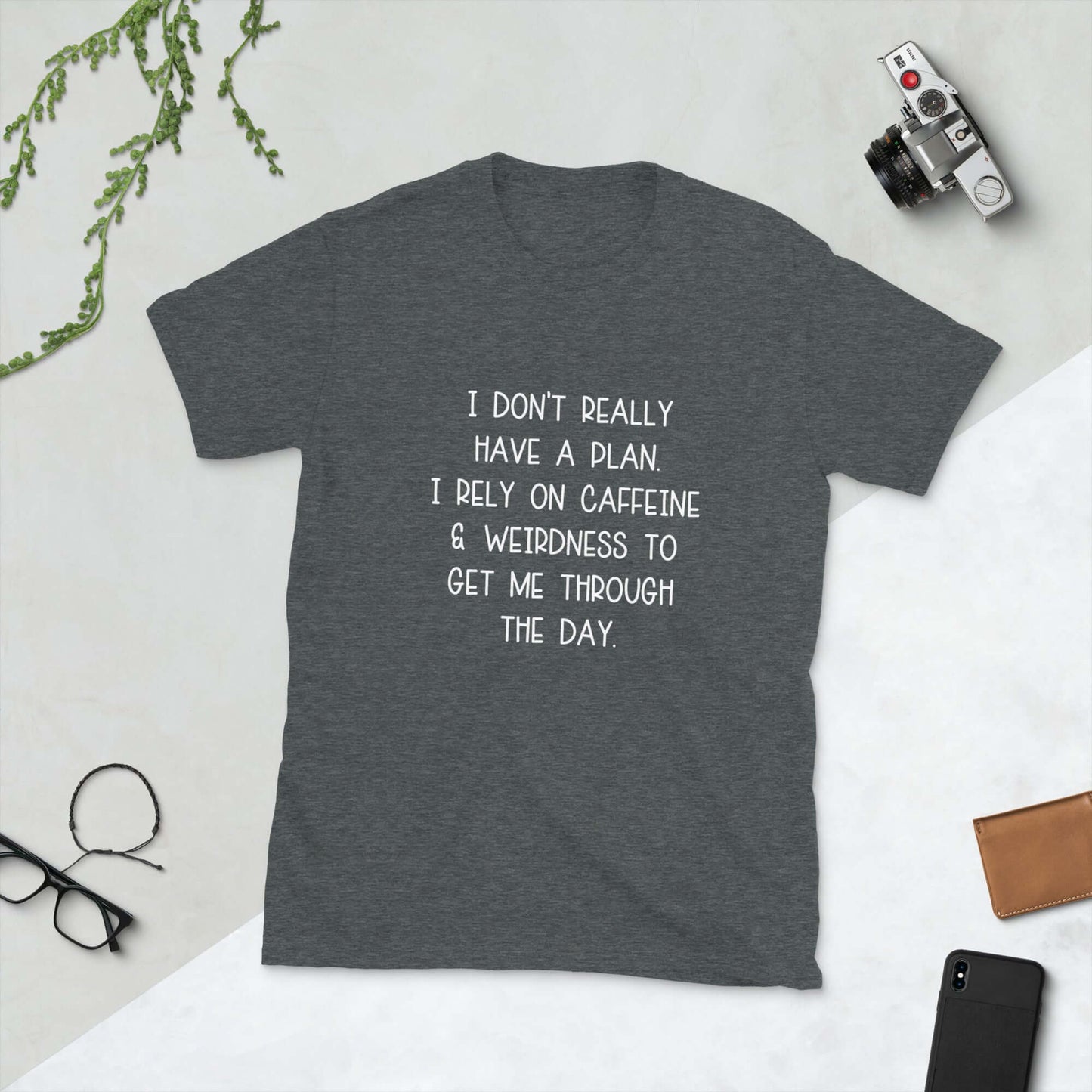Dark grey t-shirt with the words I don't really have a plan. I rely on caffeine & weirdness to get me through the day printed on the front.