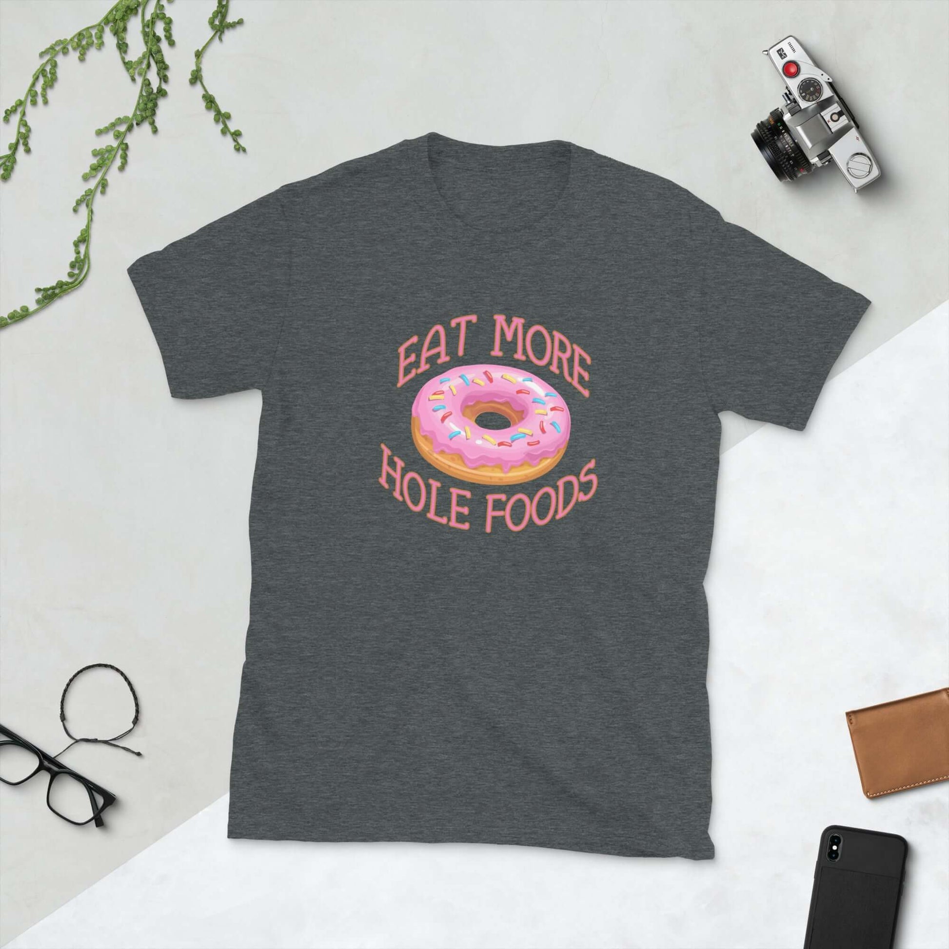 Dark heather grey t-shirt that has an image of a donut with pink icing and sprinkles and Eat more hole foods printed on the front.