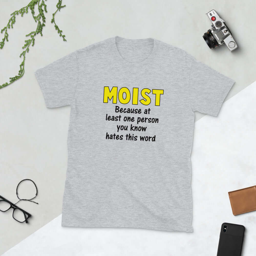 Light grey t-shirt with the word Moist printed in large yellow bold font. In smaller font under the word moist is the phrase Because at least one person you know hates this word. 