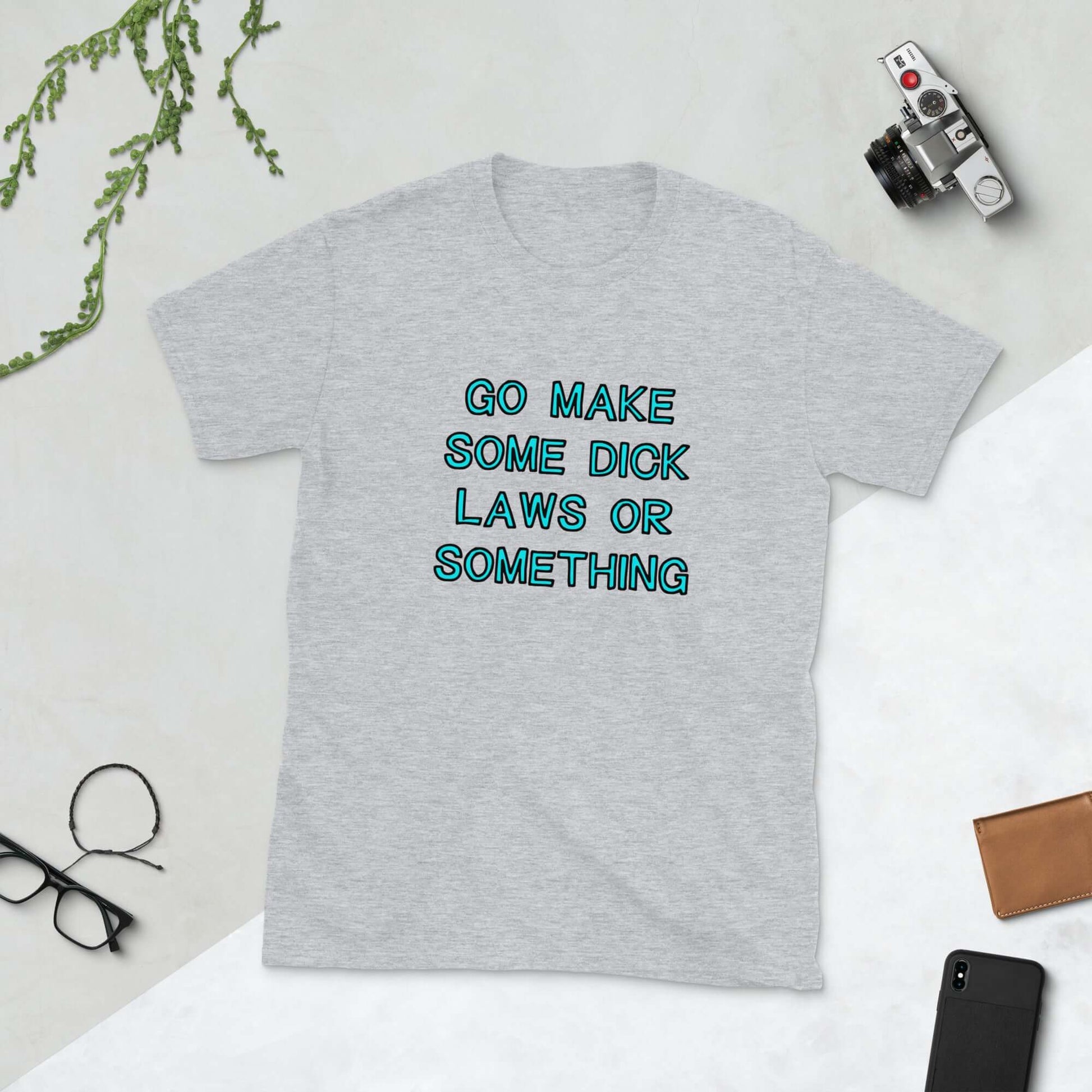 Light grey t-shirt with the words Go make some dick laws or something printed on the front. The text is turquoise with black outline.