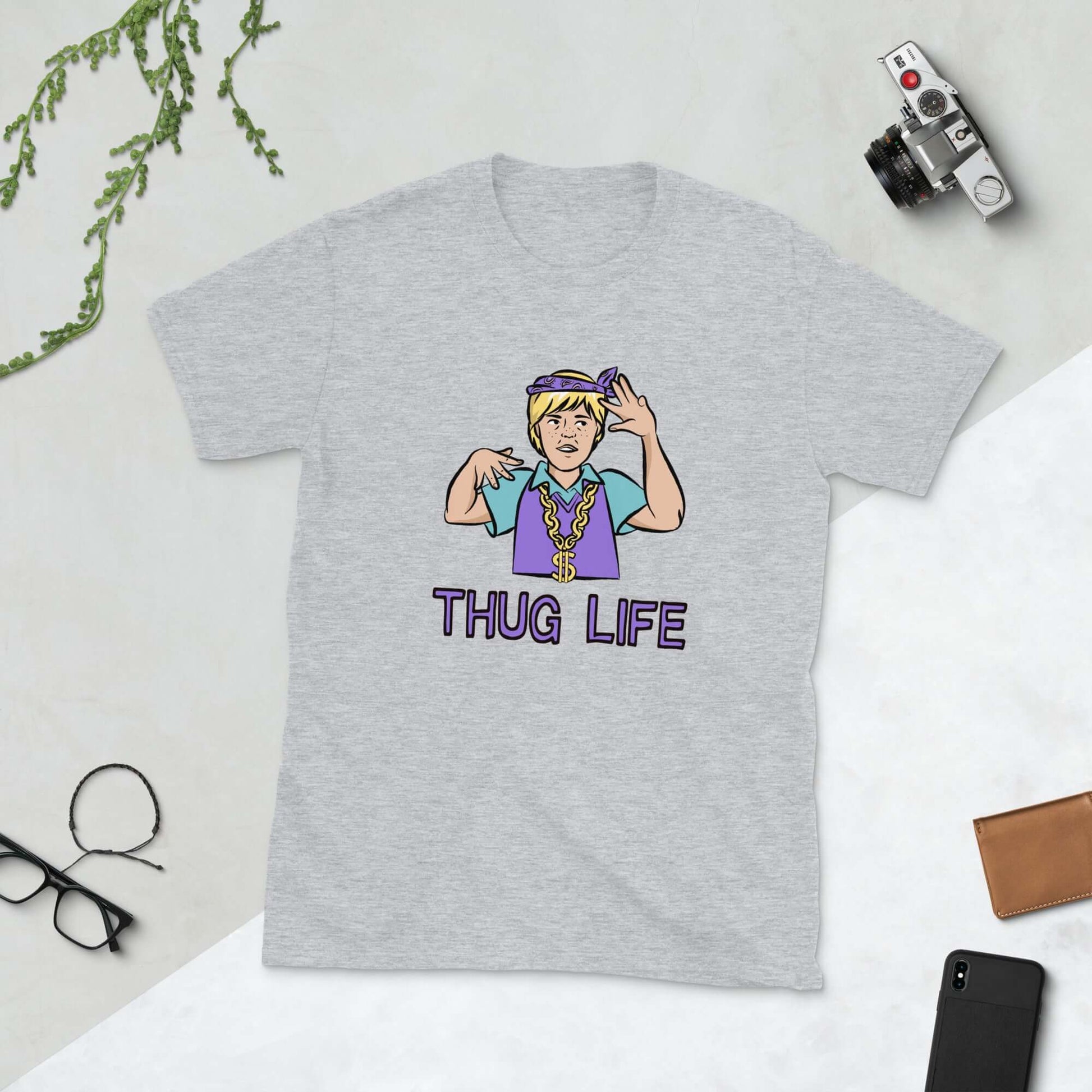 Light grey t-shirt with a parody image of a blond haired child trying to be a gangster with the words Thug Life printed on the front.