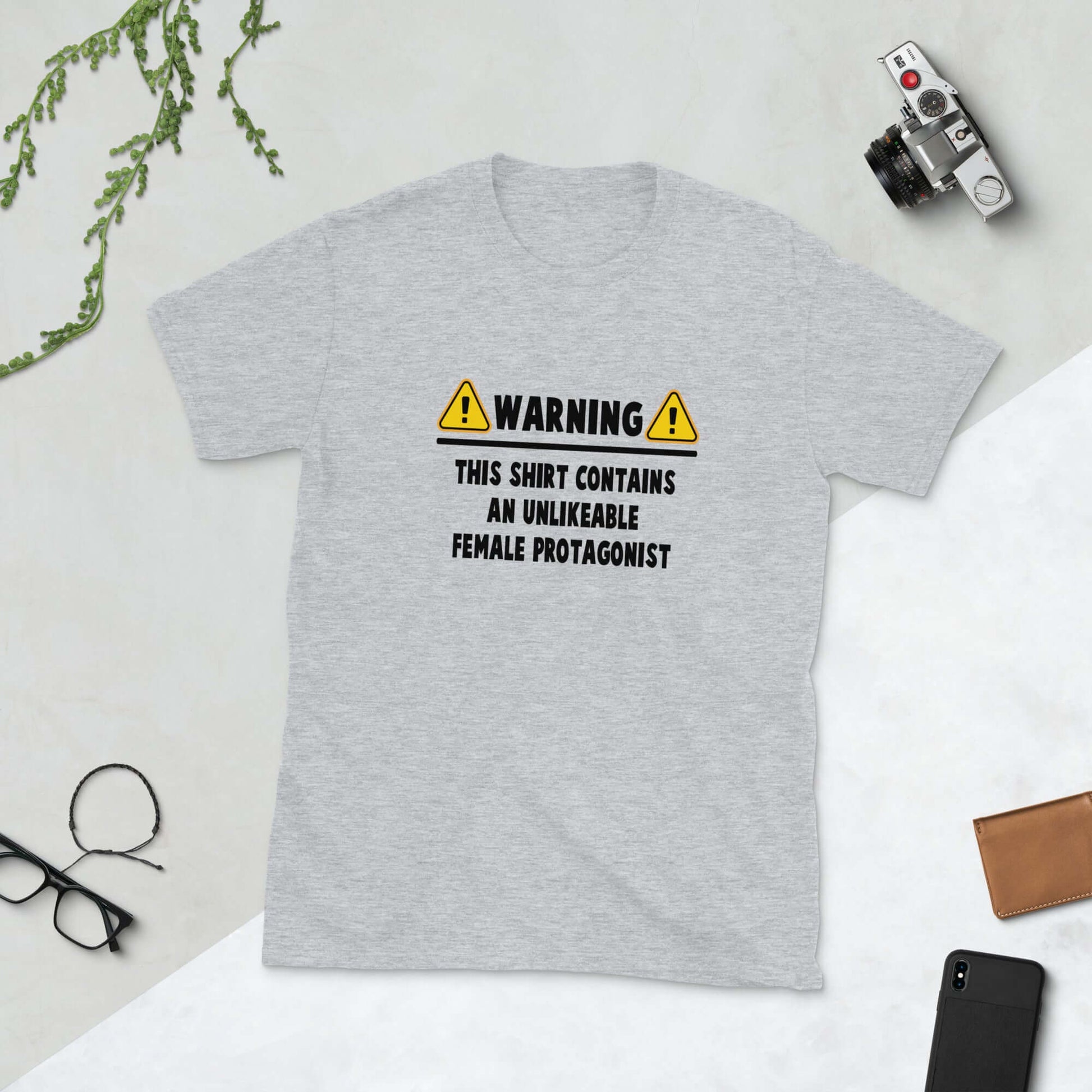 Grey t-shirt with the words Warning this shirt contains an unlikable female protagonist printed on the front.