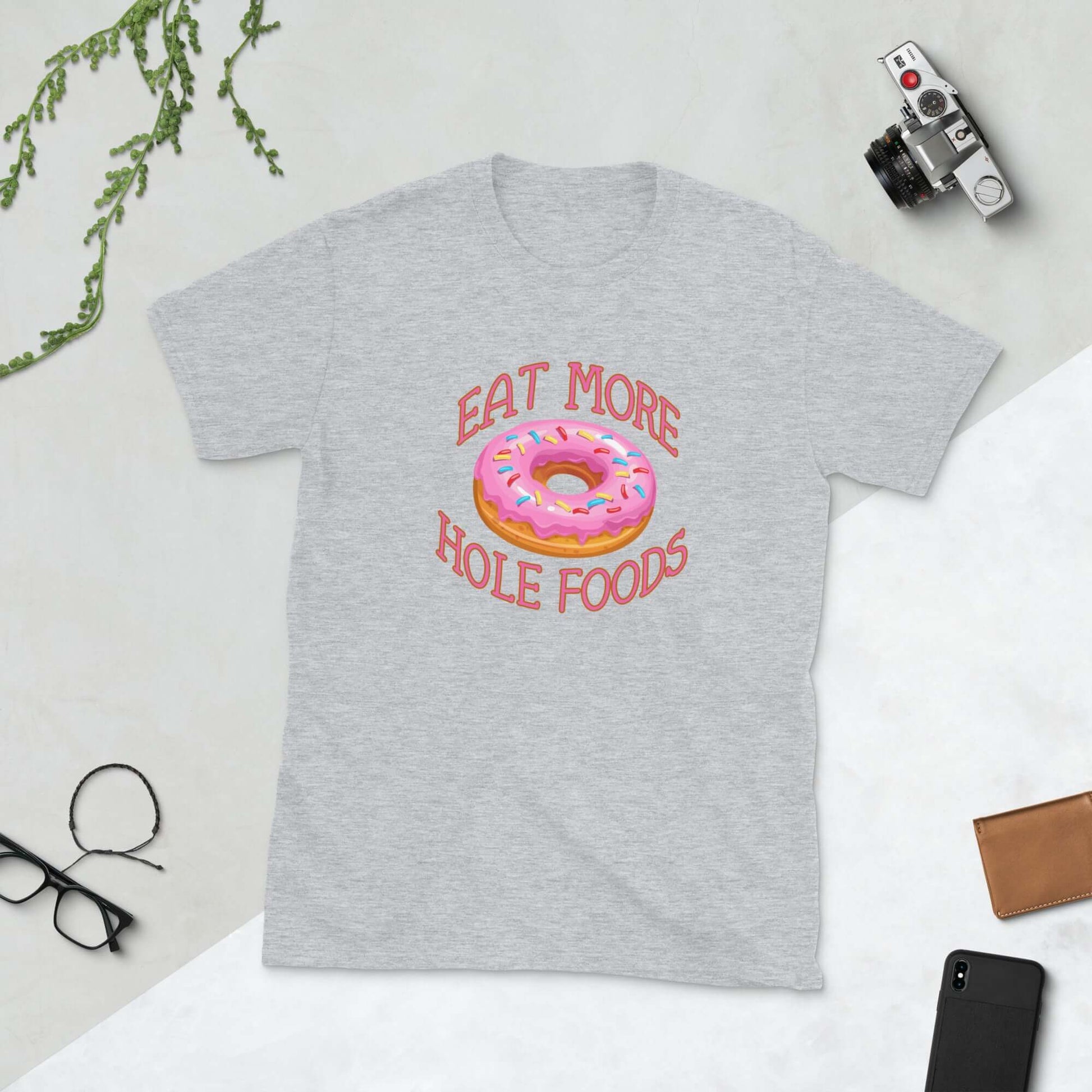 Sport grey t-shirt that has an image of a donut with pink icing and sprinkles and Eat more hole foods printed on the front.