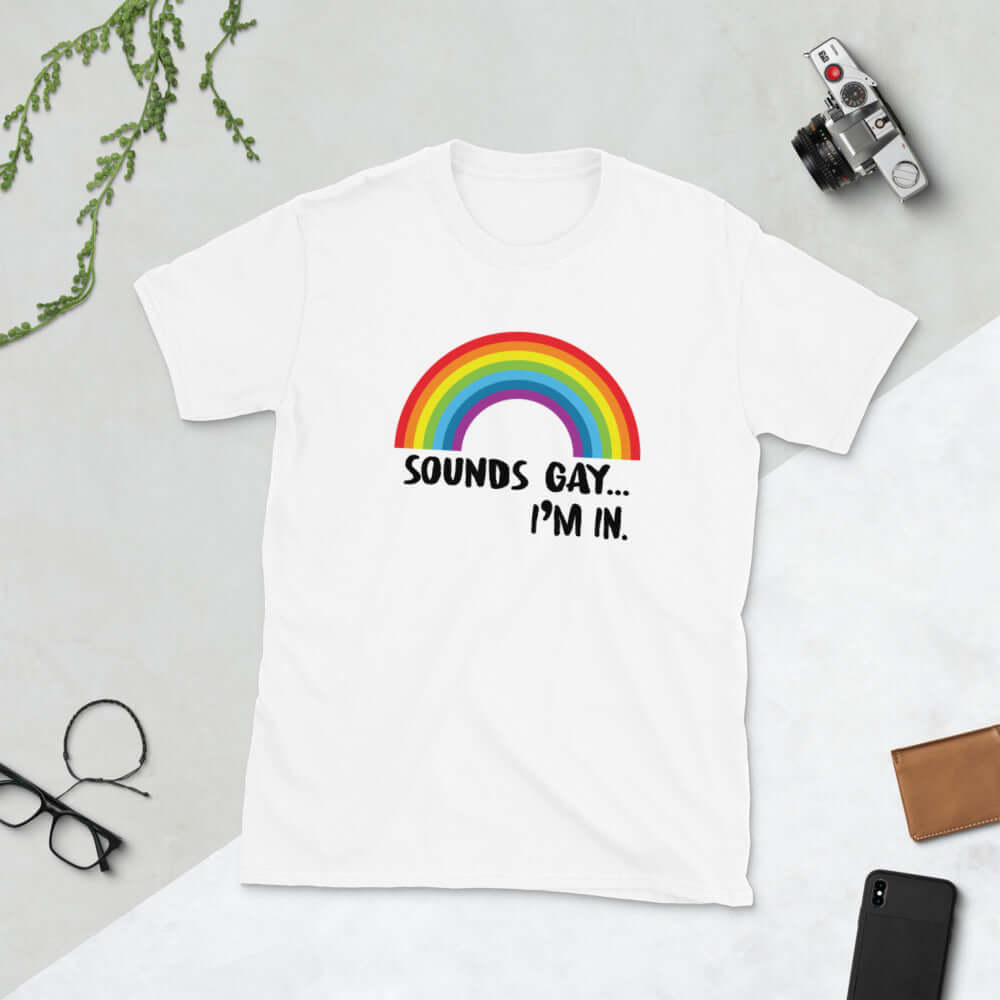 White t-shirt that has an image of a rainbow and the phrase Sounds gay, I'm in printed on the front