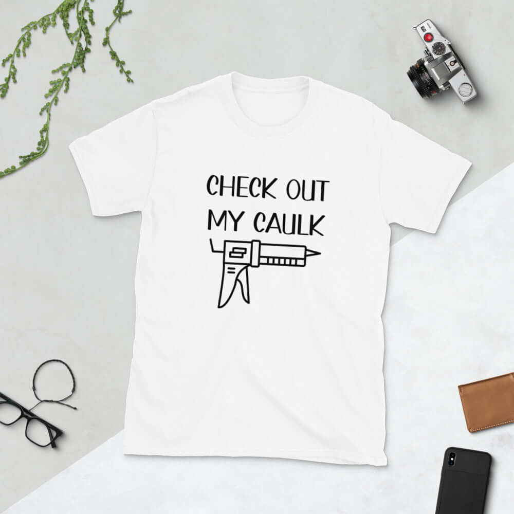 White t-shirt with the pun phrase Check out my caulk with a line drawing image of a caulking gun printed on the front.